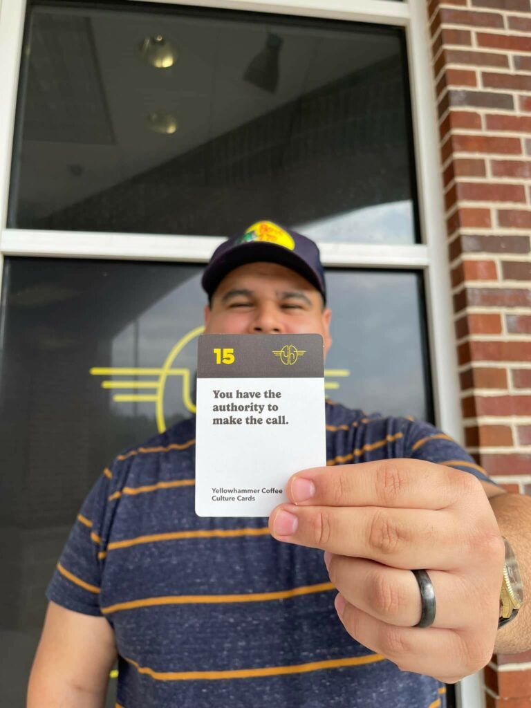 Ray, team member at yellowhammer coffee, holding a company culture card.