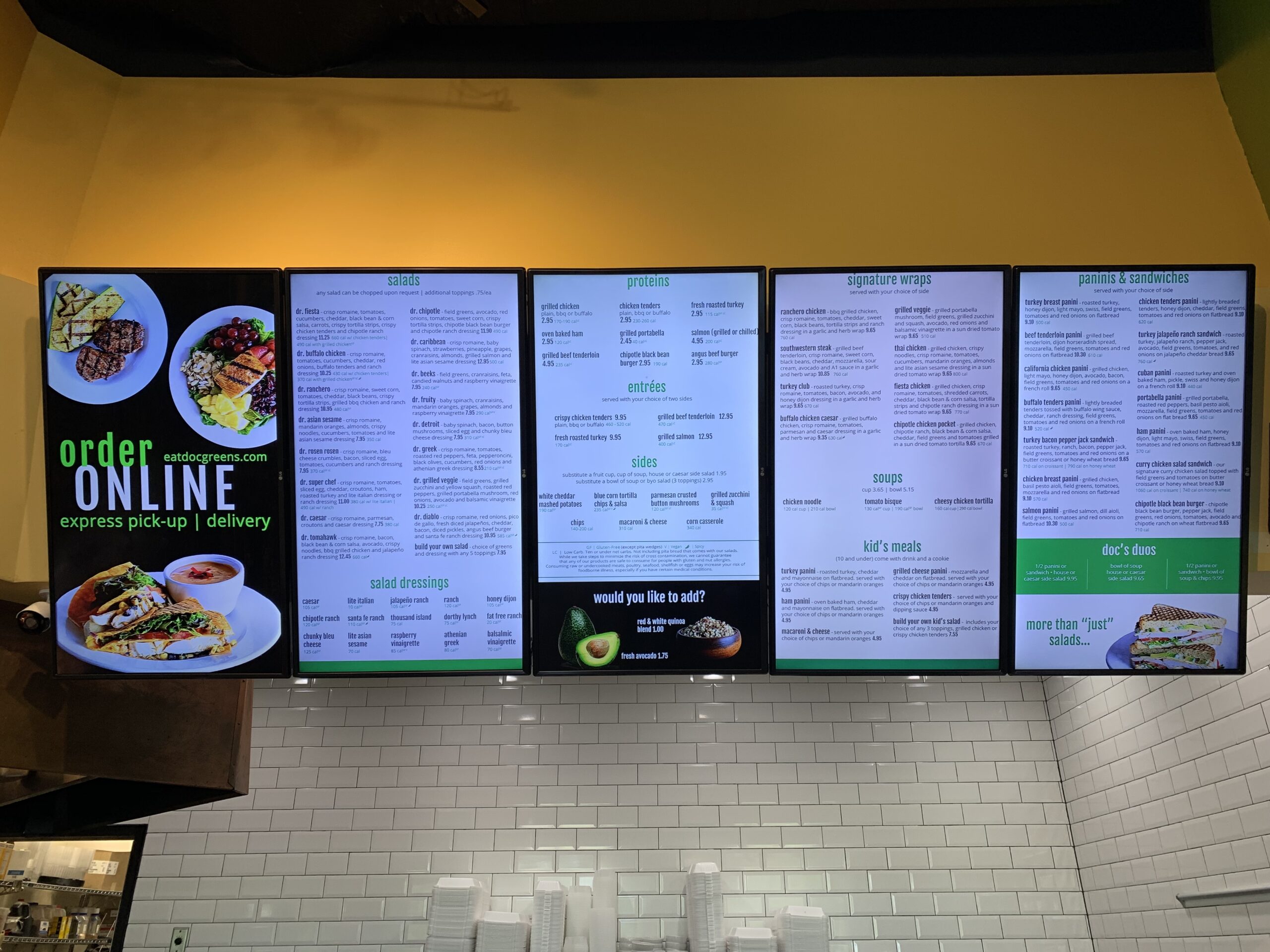 Digital menu boards displayed in a restaurant setting, showcasing vibrant images of delicious food items. The menu boards are integrated seamlessly with the Table Needs Point of Sale system.