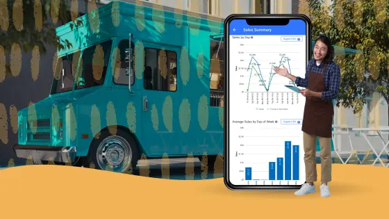 A young male food truck operator stands next to a 6-foot mobile device, showcasing his food truck's sales performance. The image emphasizes essential reporting and financial features for the best food truck POS.