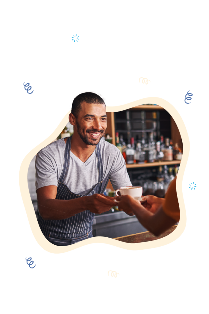 Smiling barista in a coffee shop handing over a freshly made cup to a customer, showcasing the efficient operation of a coffee shop POS system. The system is designed for quick service and ease of use, vital for the fast-paced environment of a bustling coffee shop.