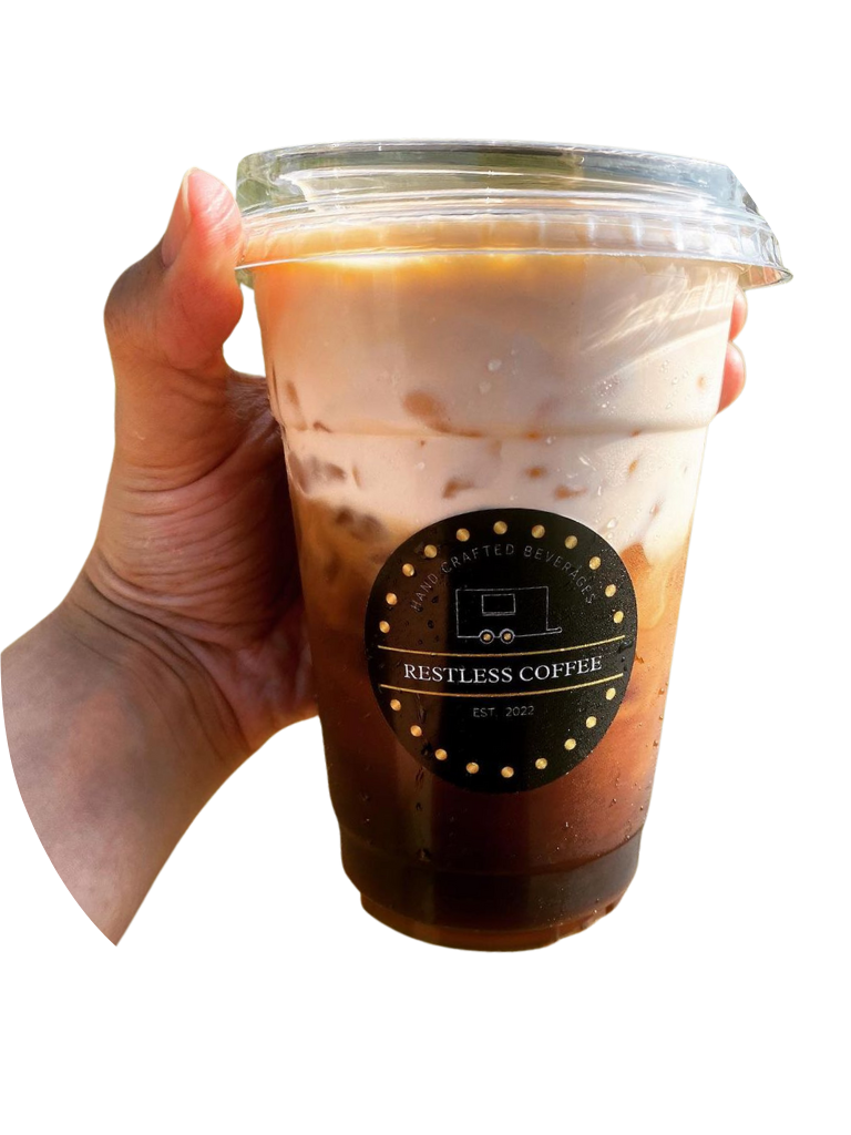 A hand holding a Restless Coffee iced beverage represents the innovation of starting a mobile restaurant with a robust food truck POS system, highlighting the seamless order process from a well-crafted menu, blending efficiency with handcrafted quality.