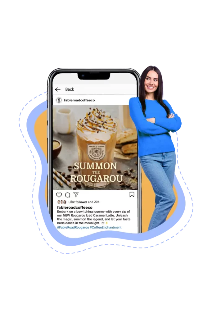 The owner of Fabel Road Coffee Co. stands smiling with arms crossed next to a smartphone screen that displays a promotional social media post from her café. The post features a delicious-looking Rougarou Iced Caramel Latte, illustrating the impact of using Table Needs’ marketing services alongside their coffee shop POS system to effectively attract and delight customers.